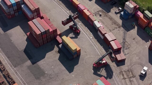 Aerial view of a busy port terminal with stacks of shipping containers and forklifts in operation, highlighting global logistics and commerce.