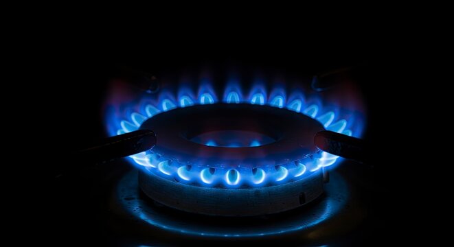Vibrant blue flame of gas stove burner against black background