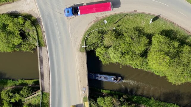 Top down aerial view of narrowboat sailing along River Trent and under bridges near Burton On Trent UK