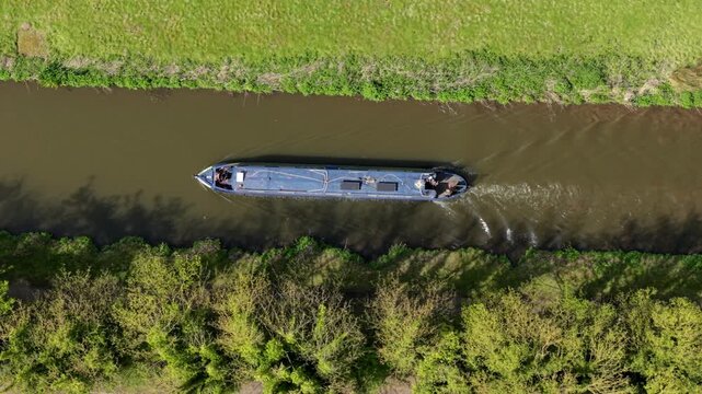 Top down aerial view of narrowboat sailing along River Trent and under bridges near Burton On Trent UK