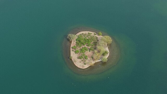 Top down aerial view of a small island on Albert Village Lake in Swadlincote, UK, featuring turquoise water