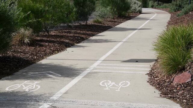 a dedicated concrete bicycle path featuring white painted bicycle symbols facing opposite directions on each side of a centre median dividing line. A two-way separated cycling lane in Australia
