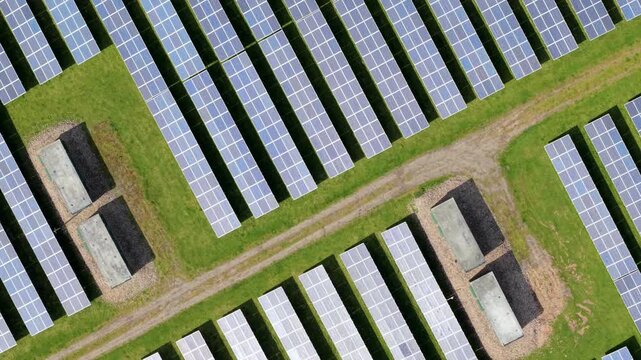Aerial view of a utility-scale solar farm with symmetrical rows of cells, showcasing advanced renewable energy infrastructure and transformer units in Tutbury, UK.