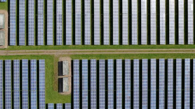 Aerial view of a utility-scale solar farm with symmetrical rows of cells, showcasing advanced renewable energy infrastructure and transformer units in Tutbury, UK.
