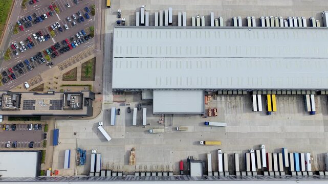Top down aerial view of large distribution warehouses and HGVs at loading bays UK
