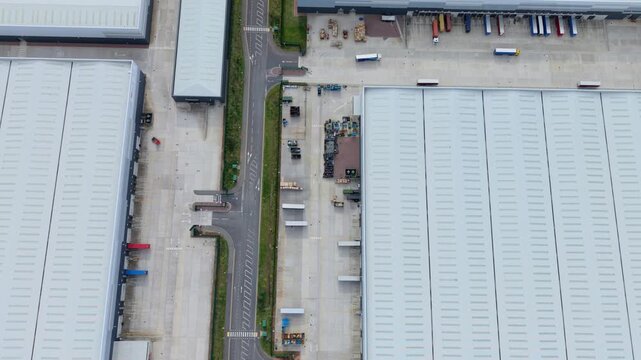 Top down aerial view of large distribution warehouses and HGVs at loading bays UK