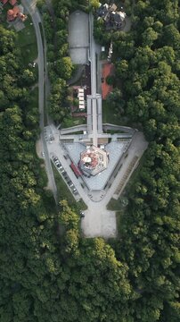 Top view aerial of the triangular base of Avala tower surrounded by a lush green forest, Belgrade, Serbia. Vertical video.