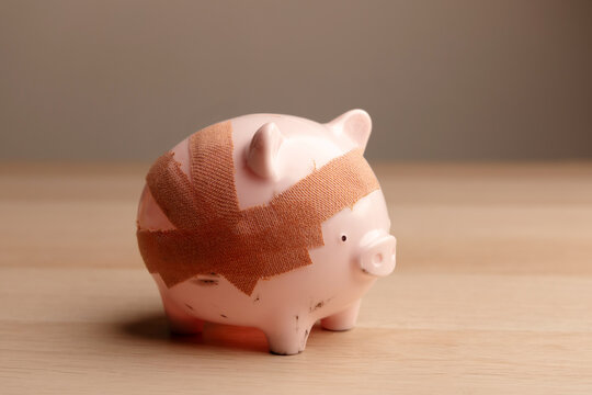 Damaged piggy bank with bandage, Fragile economy and financial crisis