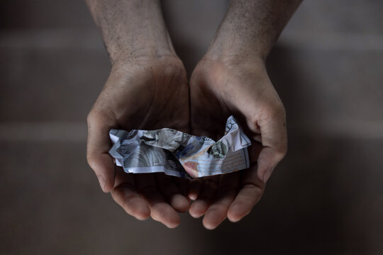Dirty hands holding crumpled dollar bills, Poverty and inequality