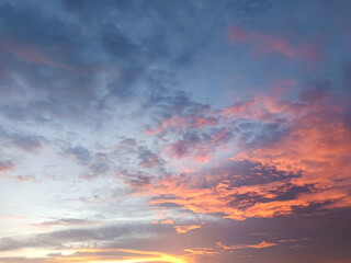 Fototapeta premium Dramatic Colorful sunset sky with soft blue clouds and glowing pink-orange hues, creating a serene and dreamy atmosphere. Ideal as a natural background or atmospheric landscape.