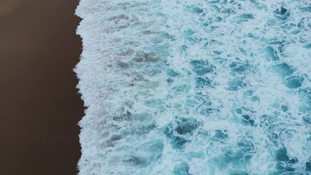 Ocean waves crashing on sandy beach creating beautiful patterns with foamy whitecaps motion footage.