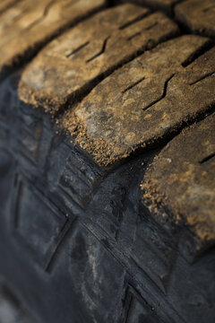 View of the worn tire tread, textured with grime and grit, against the dark rubber, hinting at journeys through rugged landscapes, Skaftarhreppur, Iceland.