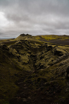 View of moss-covered lava fields stretch toward the horizon under a cloudy sky, showcasing rugged beauty, Skaftarhreppur, Iceland.