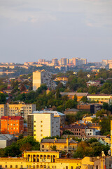 Obraz premium Dnipro, Ukraine, a panoramic cityscape showcasing an urban landscape with diverse residential and commercial buildings, lush green trees, and golden hour light illuminating the structures under a soft