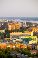 Fototapeta premium Dnipro, Ukraine, cityscape at golden hour with the Dnieper River and residential buildings, industrial structures, and a bridge under a hazy sky, capturing urban life and nature blend Includes copy sp