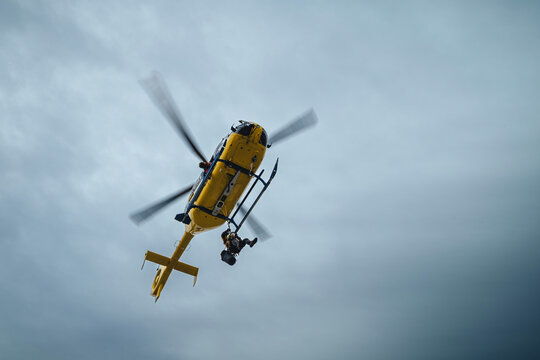 Paramedic hanging on rope under flying helicopter emergency medical service. Themes rescue, help and heroes. Sky with copy space..