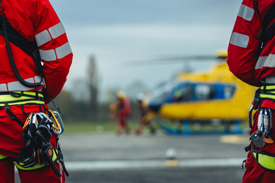 Team of helicopter emergency medical service on helipad. Doctor and paramedics with safety harness and climbing equipment against helicopter. Themes rescue, help and hope.