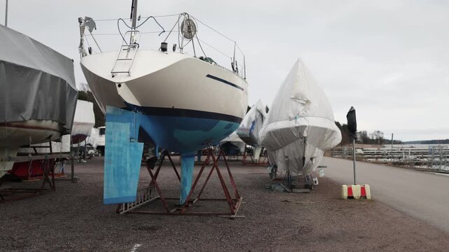 Yachts stored on land under tarps on stands coastal marina off season boat storage maintenance and protection concept maritime industry calm harbor environment