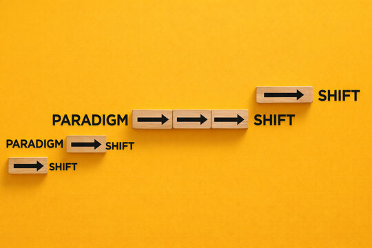 Wooden blocks with black arrows show a progression of the paradigm shift concept arranged in an ascending step pattern against a saturated yellow background for business.