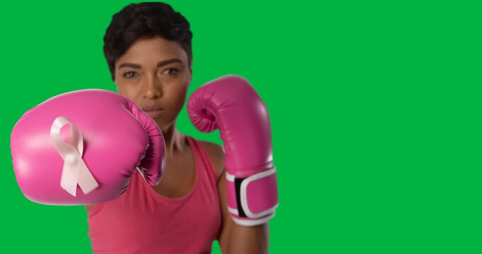 African american female boxer with ribbon badge on pink boxing gloves against black background