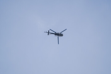 Fototapeta premium Military or Utility Helicopter with Rotor Blur Flying in a Clear Blue Sky