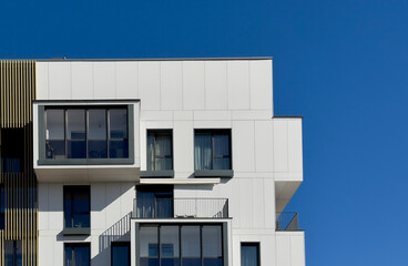 Modern building facade stands against clear blue sky. Contemporary architecture shows minimal...