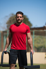 Fototapeta premium Middle Eastern man training strength and CrossFit in an outdoor gym wearing red shirt with a friend nearby