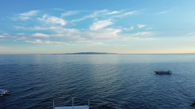 Tranquil seascape with gentle waves under a clear blue sky, viewed from Panglao, Philippines. Peaceful horizon and distant landmass create a serene atmosphere.