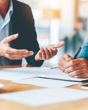Empathy communication conflict management over shoulder perspective of professional writing note during meeting no faces visible quiet workspace neutral tones soft lighting