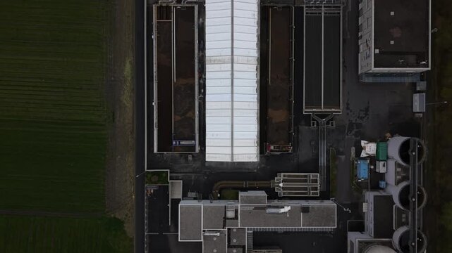 Top down aerial view of rectangular basins showing different stages of wastewater filtration, with water gradually becoming cleaner across multiple treatment sections