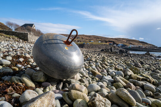 Bouy washed uo on the pebble covered beach at Elgol with the harbour behind
