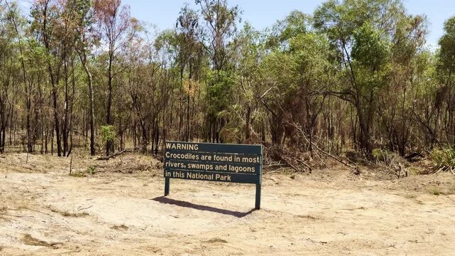 green wooden sign warning about crocodiles in rivers, swamps and lagoons in Cape York, northern Queensland, Australia. Tropical hazard and wildlife safety concept.