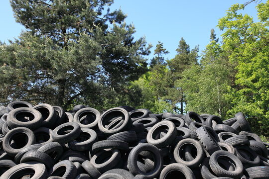 A chaotic pile of old automobile tires dumped in a scenic landscape, turning a natural spot into a wild junkyard.