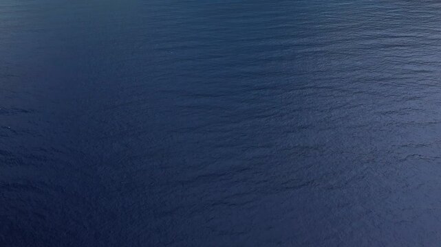 Drone shot of Plage de Nonza, featuring turquoise waves, a wide pebble beach, and lush green hills in Corsica, France.