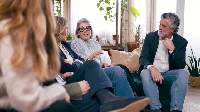 Cheerful group of senior friends sitting on a sofa and talking. Mature people having a pleasant conversation while relaxing together at home