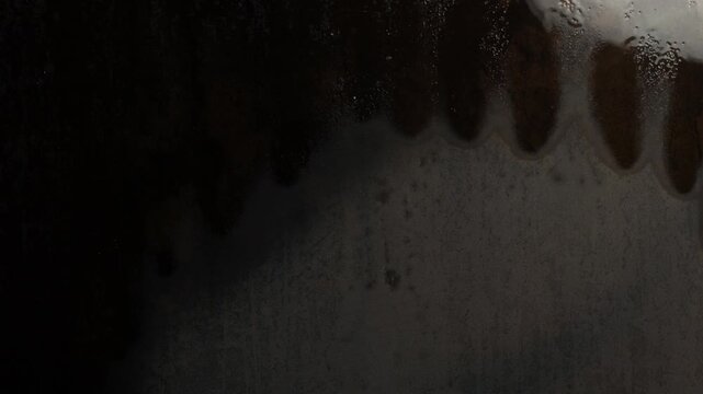 The dark wall gradually becomes completely wet. Dark background. 4k video
