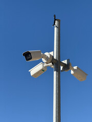 Surveillance cameras mounted on a metal pole under clear blue sky strong lighting background © dvoevnore