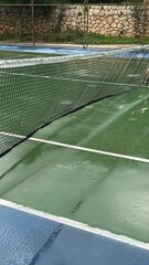 Tennis court with green surface and net, suitable for sports-themed backgrounds © dvoevnore