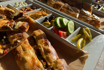 Turkish pide and assorted appetizers served on a platter under warm sunlight. © dvoevnore