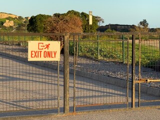 Exit only sign on metal gate with scenic outdoor background and pathway visible behind gate © dvoevnore