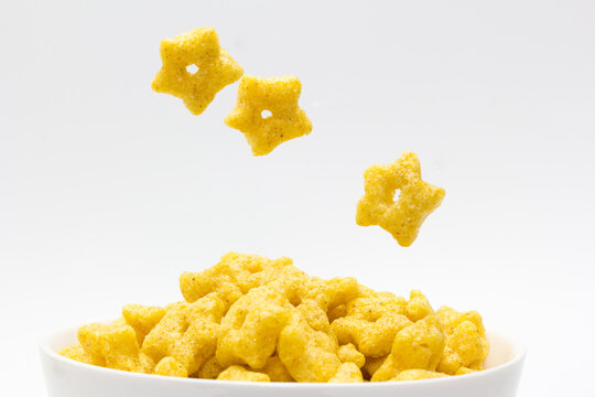 Cereal en forma de estrella cayendo en un bol sobre fondo blanco