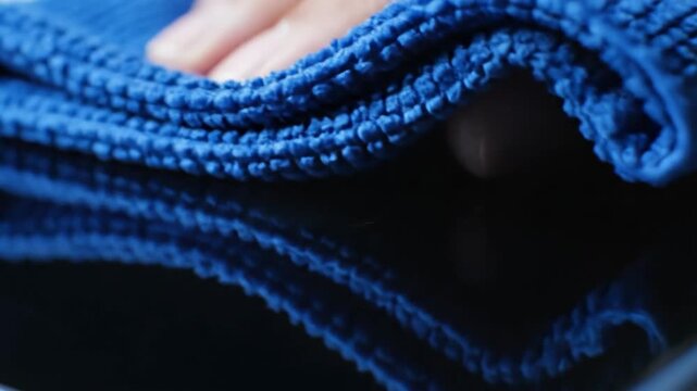 Wiping a smooth surface with a blue microfiber cloth
