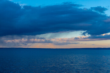 Fototapeta premium Amazing sunset seen over Lake Constance near the city of Rorschach in the Sankt Gallen region in Switzerland with an impressive rolling cloudscape full of unpredictable weather and snow showers in ear