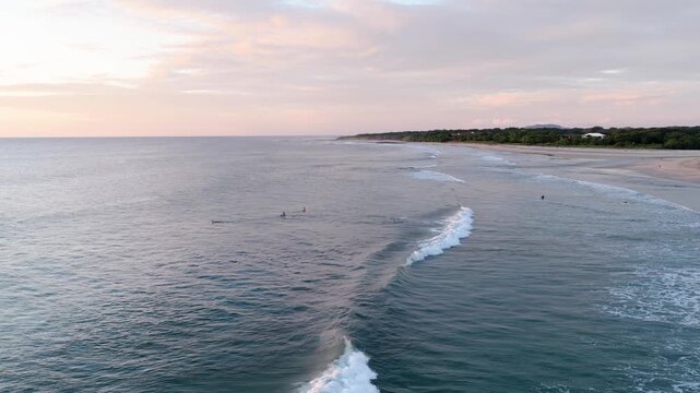Beautiful aerial view showing a surfer riding a long wave at avellanas beach in costa rica, with other surfers waiting in the lineup