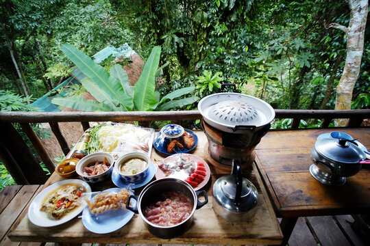 Top view of Moo Krata set, Thai food and Barbecue set on wooden table on terrace and tropical forest in Thailand
