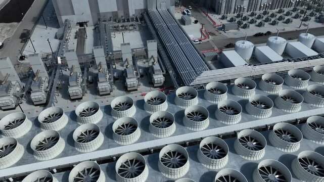 Pan up of an AI Datacenter cooling towers, piping and electrical equipment. Chilling towers are on both sides of the building in a remote area and an electrical substation on the side