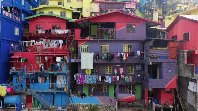 Vibrant, multi colored residential buildings with laundry hanging outside in the Vallee des couleurs de Baguio, Philippines. Urban community scene with lively architecture and daily life details.