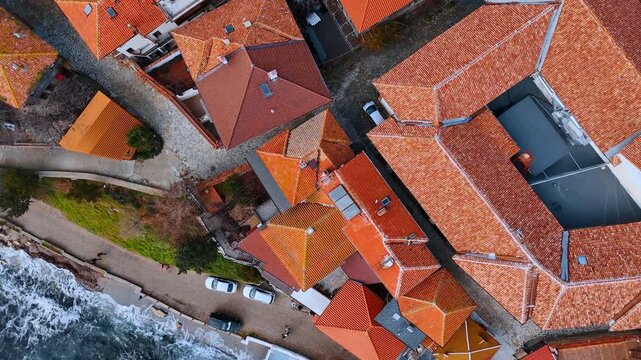 Top down aerial shot of traditional house roofs. Overhead view of terracotta tiled roofs and narrow paved street