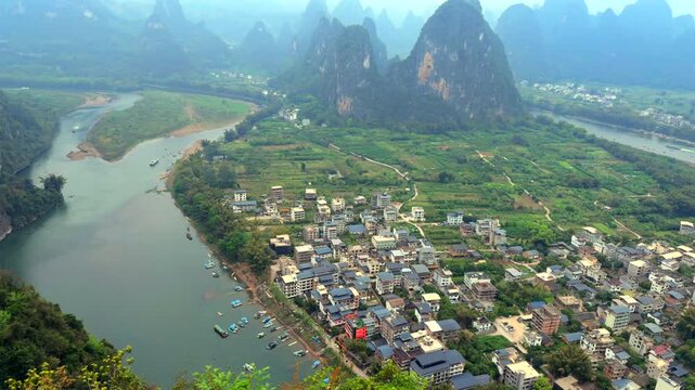 Guilin China, Li River winding through karst mountains and village, breathtaking majestic atmosphere.showing the winding Li River and limestone peaks with a local village, suitable for travel document