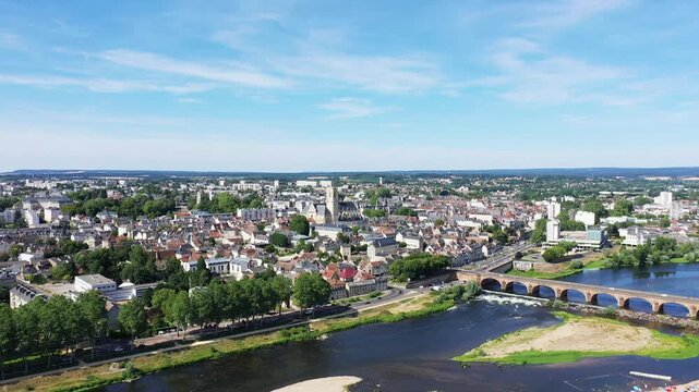 Scenic aerial panorama of Nevers, France, featuring the historic city, a stone bridge, and the Loire River under a clear blue sky.